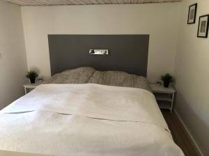 1 dormitorio con 1 cama blanca grande y 2 mesas en Hyggelig ferielejlighed, en Skagen