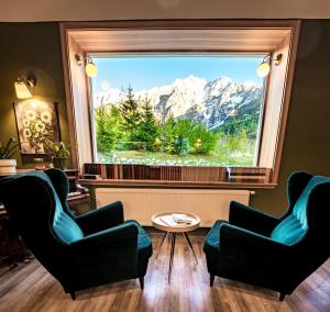 a room with two chairs and a window with a mountain view at Vila Koman Jezersko in Zgornje Jezersko