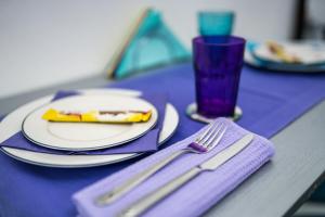 einen Tisch mit einem Teller Essen und einer lila Serviette in der Unterkunft Apartment Tesla Wizard in Belgrad