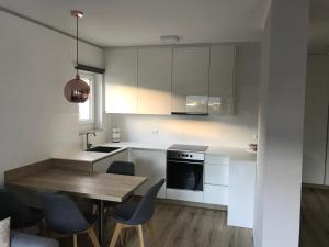 une cuisine avec des placards blancs et une table et des chaises en bois dans l'établissement Apartment Mathilda, à Bolzano