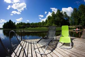 deux chaises assises sur un quai à côté d'une masse d'eau dans l'établissement Brīvdienu māja Ezera Sonāte, à Bērzgale