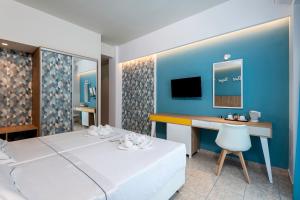 een slaapkamer met een bed, een bureau en een televisie bij Olympia Hotel in Kos-stad