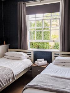 two beds in a room with a window at The Blue Mantle in Wellington