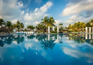 una gran piscina con palmeras en el fondo en Vidanta Riviera Maya, en Puerto Morelos
