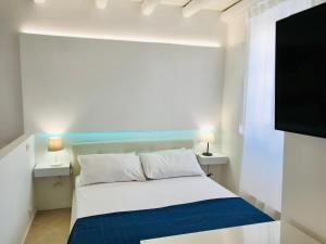 Cette chambre comprend un lit avec deux lampes et une télévision à écran plat. dans l'établissement Casa vacanza Apollodoro, à Syracuse