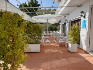 eine Terrasse mit weißen Tischen, Stühlen und Pflanzen in der Unterkunft Pension los Verdiales in La Herradura