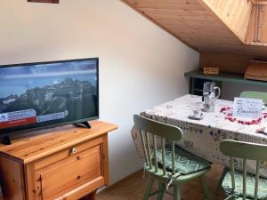 a dining room with a tv and a table with chairs at Bachlaufen Haus in Sesto
