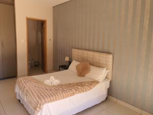 1 dormitorio con 1 cama grande con sábanas y almohadas blancas en Maraba Manor, en Vryburg