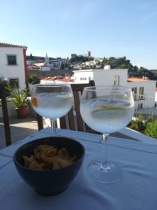 Dois copos de água e uma tigela de batatas fritas numa mesa. em adubai Obidos em Óbidos
