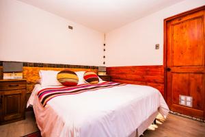 - une chambre avec un lit blanc et des murs en bois dans l'établissement Hotel Casa Algarrobo, à San Pedro de Atacama