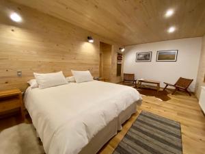 a bedroom with a large white bed and wooden walls at Line Hotel Patagonia in Puerto Natales