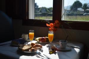 Hotel Las Catedrales في Pumarín: طاولة مع طعام الإفطار وكأسين من عصير البرتقال