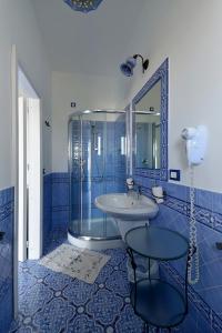uma casa de banho azul com um lavatório e um chuveiro em Hotel A Cannata em Santa Marina Salina