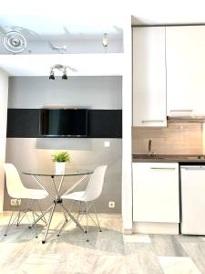 a kitchen with white cabinets and a table and chairs at Apartamentos Puerta Del Sol in Madrid