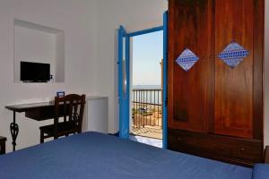 a bedroom with a door open to a balcony with a desk at Hotel A Cannata in Santa Marina Salina