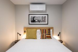 a bedroom with a white bed with two lamps at AVENUE MOTEL APARTMENTS in Toowoomba