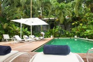 una piscina con tumbonas y sombrilla en Le Cameleon Boutique Hotel, en Puerto Viejo