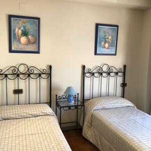 two beds in a bedroom with two pictures on the wall at La casa de Tita Elvira 2 in Zafarraya