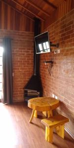 a room with a bench and a tv on a brick wall at Chalés Roma in Santo Antônio do Pinhal