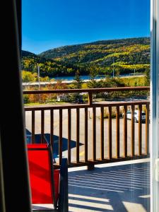 a red chair on a balcony with a view of the water at Hôtel Motel Le Beluga in Tadoussac
