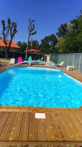 a large blue swimming pool with a wooden deck at Villa en pleine nature à Escource avec piscine privée in Escource