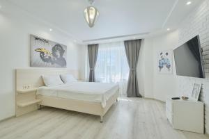 a white bedroom with a bed and a tv at Apartment Petrovskie on Frunze 46 in Tomsk
