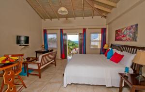 een slaapkamer met een bed, een tafel en een stoel bij Grooms Beach Villa & Resort in Saint Georgeʼs