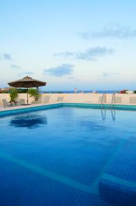 a large blue swimming pool with an umbrella at Hotel Los Itzaes by 5th av in Playa del Carmen