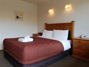 a bedroom with a large bed with a red blanket at Rosewood Court Motel in Christchurch