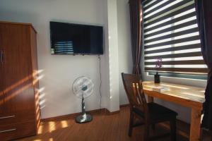 a room with a desk and a fan and a window at Nhà của Elly in Danang