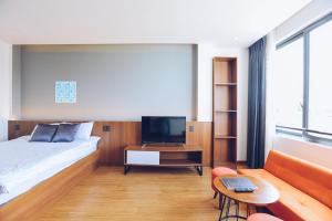 TTR Studio Apart Hotel في دالات: غرفة نوم بسرير وتلفزيون وأريكة