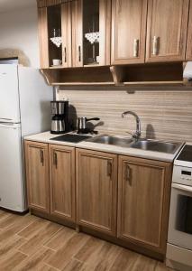 eine Küche mit Holzschränken, einer Spüle und einem Kühlschrank in der Unterkunft Kamares Stone House 1 in Álika