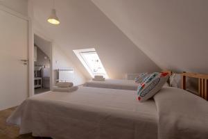 a white bedroom with two beds and a window at Casa Carolina in Vila Real de Santo António