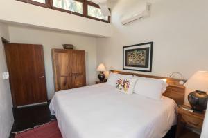 een slaapkamer met een wit bed en een houten deur bij Villas Carrizalillo in Puerto Escondido