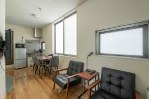 ein Wohnzimmer mit einem Tisch, Stühlen und Fenstern in der Unterkunft bmj Hyakunincho in Tokio