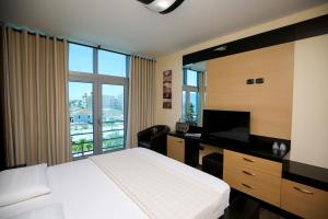 a bedroom with a bed and a desk with a television at Hotel Vlora International in Vlorë