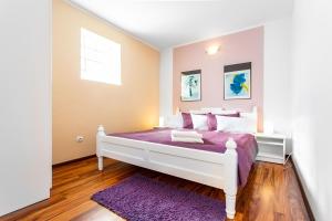 sypialnia z białym łóżkiem z fioletową pościelą i oknem w obiekcie Plaża Apartament w mieście Ustronie Morskie