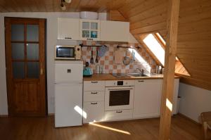 a kitchen with white appliances and a wooden ceiling at Chata Harmonie in Bedřichov