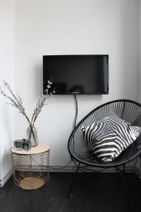 een zwarte stoel met een kussen en een tv aan de muur bij Suite César in Gent