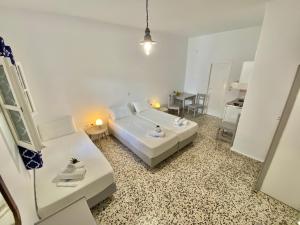 a white bedroom with a bed and a table at Anna Studios in Katapola
