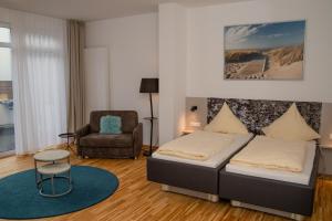um quarto com uma cama e uma cadeira em Hotel Jann von Norderney em Norderney