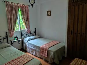a bedroom with two beds and a window at Cortijo la Joya in Cómpeta +13 photos