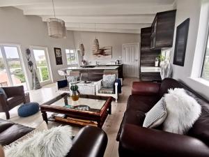 sala de estar con muebles de cuero y piano en The Blue Dragonfly, en Jeffreys Bay
