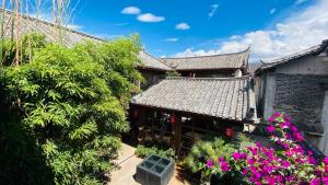 a building with purple flowers in front of it at Xilu Xiaoxie Inn in Lijiang