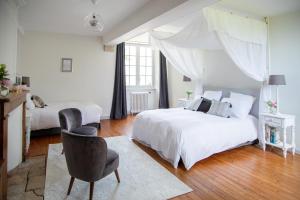 Un dormitorio blanco con 2 camas y una silla en Le Manoir De Juganville, en Saint-Martin-de-Varreville