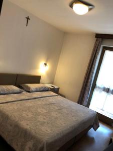 een slaapkamer met 2 bedden en een kruis aan de muur bij Hotel Nevada in Campitello di Fassa