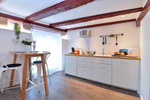 cocina con armarios blancos y mesa de madera en La stub de la Petite Venise, en Colmar