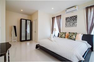 a bedroom with a large white bed with windows at Baan Marwin Hua Hin in Hua Hin