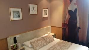una camera con un letto e un dipinto di una donna di Hotel Mignon ad Avignone