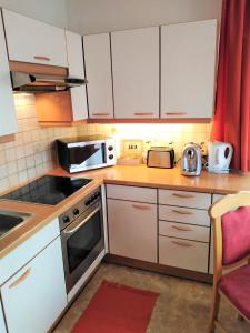 a small kitchen with white cabinets and a microwave at Ferienwohnung Nagy in Innsbruck